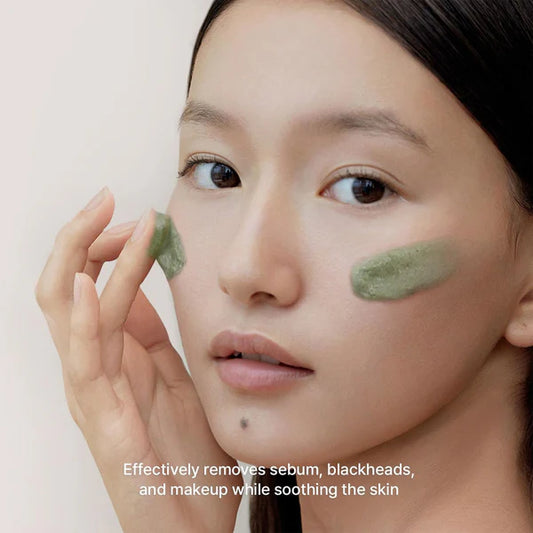 Woman applying green facial mask with text on a light background