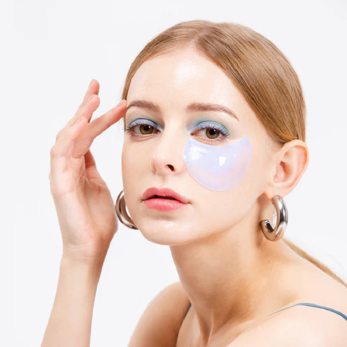 Woman wearing eye patches with a plain background