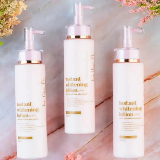 Three bottles of instant whitening lotion on a marble surface with floral decorations.