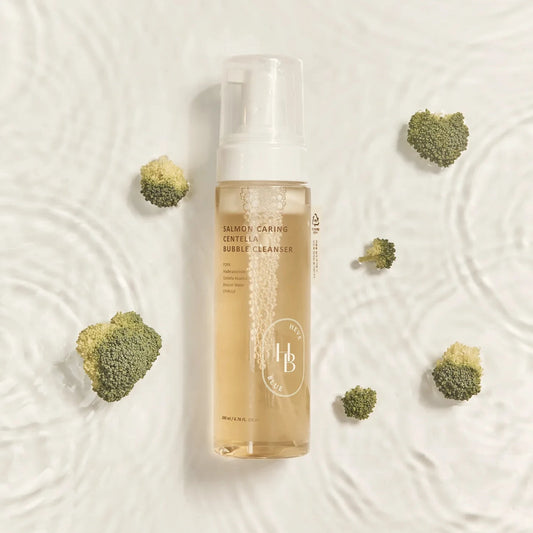Bottle of facial cleanser with broccoli on a textured beige background