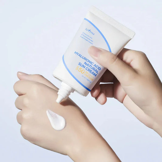 Hand applying sunscreen cream to another hand with a white background
