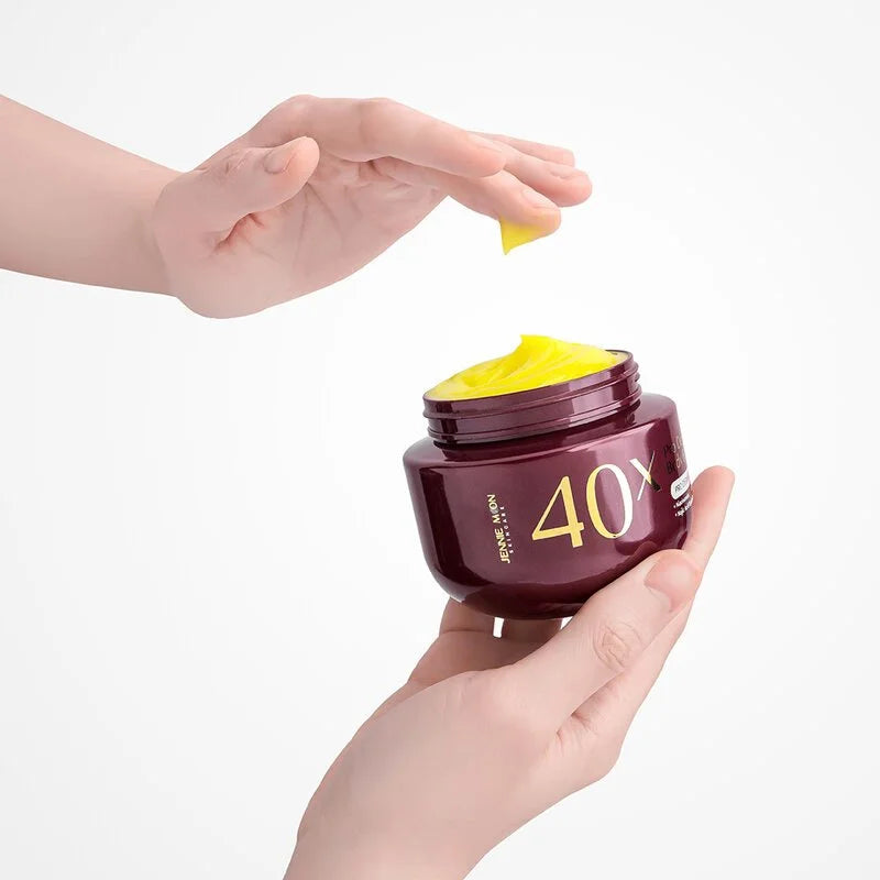 Hand holding a jar of yellow cream labeled '40X', with another hand scooping out some cream.