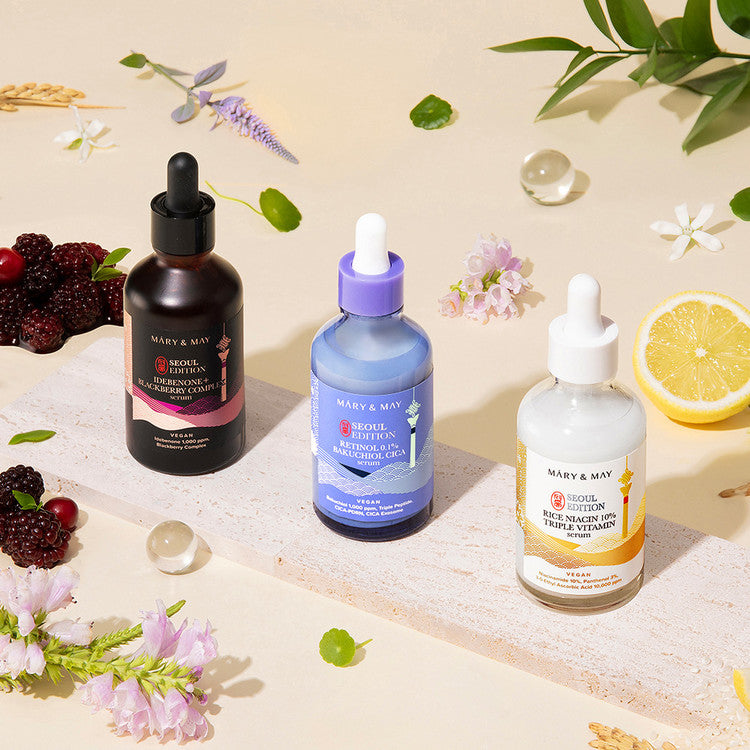 Three skincare dropper bottles on a light background with fruits and flowers.