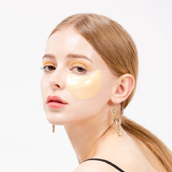 Woman wearing yellow eye patches on a white background