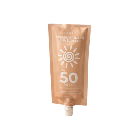 Tube of Adorn Premium Tinted Sunscreen SPF 50 on sand with a swatch.