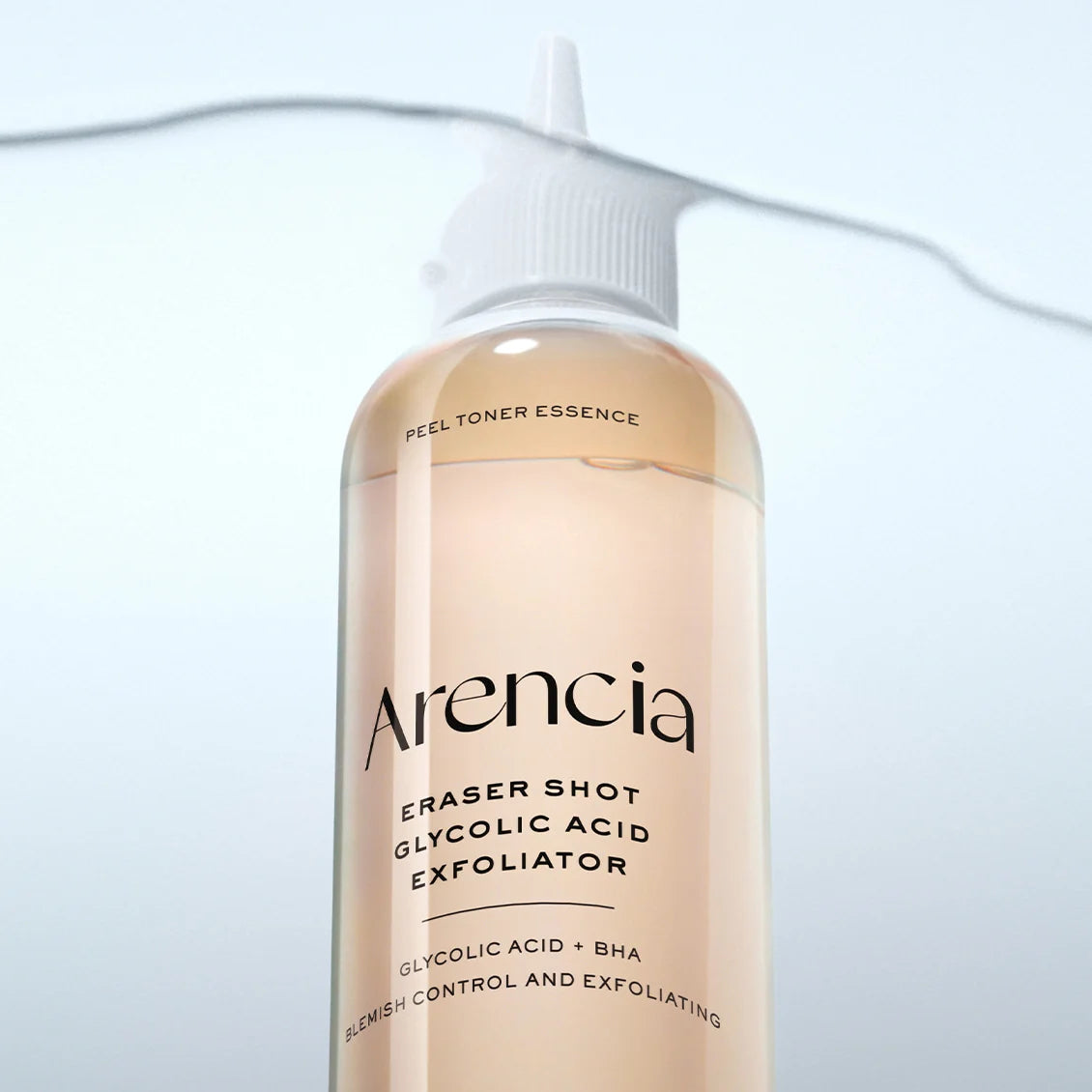A clear plastic squeeze bottle of Arencia Eraser Shot Glycolic Acid Exfoliator with a white cap, filled with a pale peach-colored liquid, set against a light blue background with a thin black line.