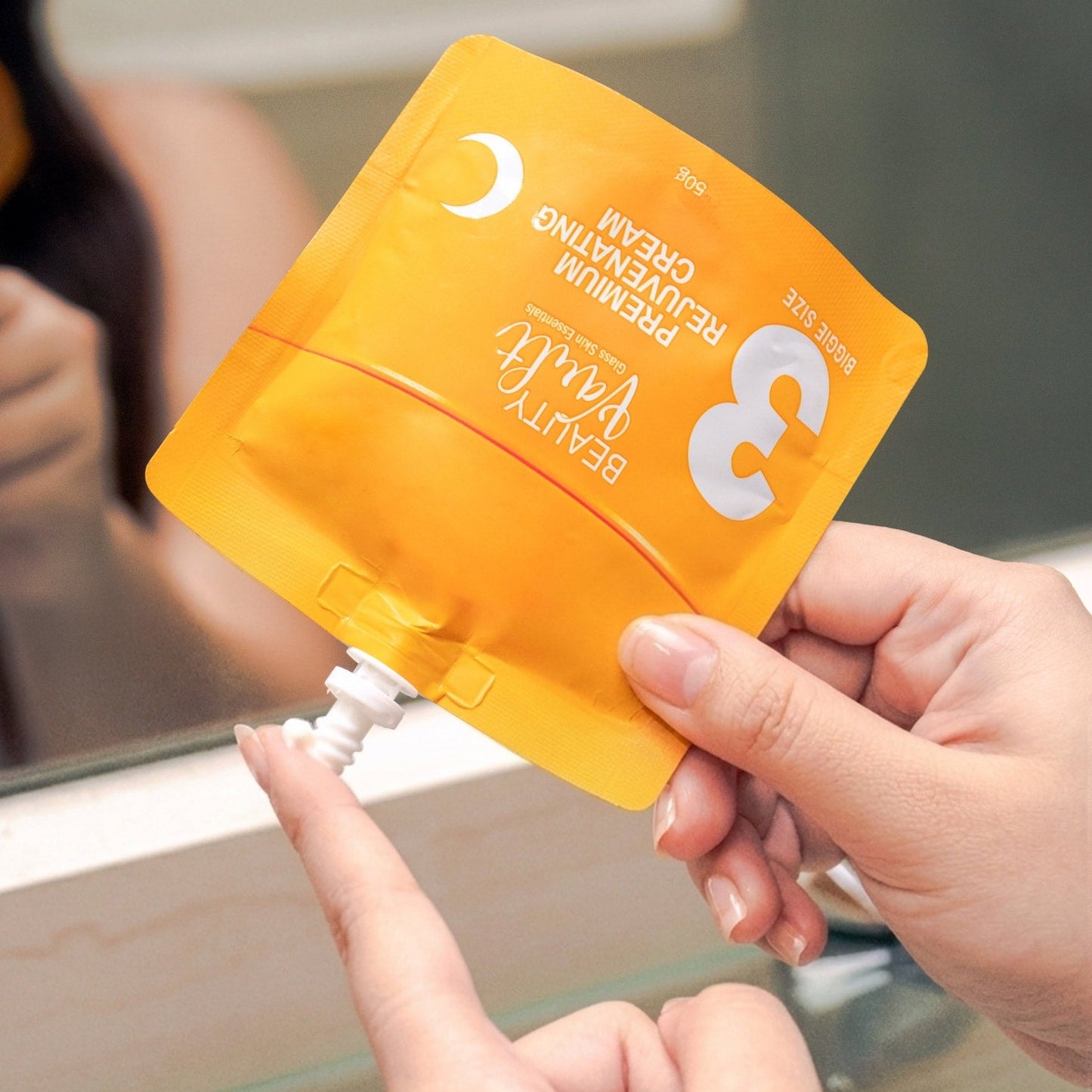 Person holding a yellow skincare product packaging with a mirror in the background