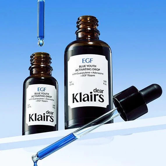 Two bottles of Klairs EGF Blue Youth Activating Drops with droppers on a blue and white gradient background.