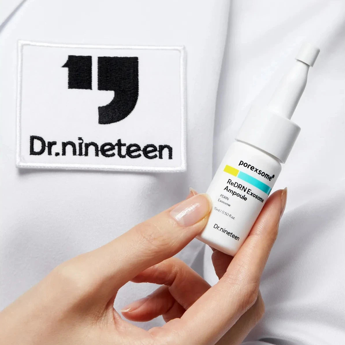 Hand holding a Dr. Nineteen skincare product with a white lab coat background
