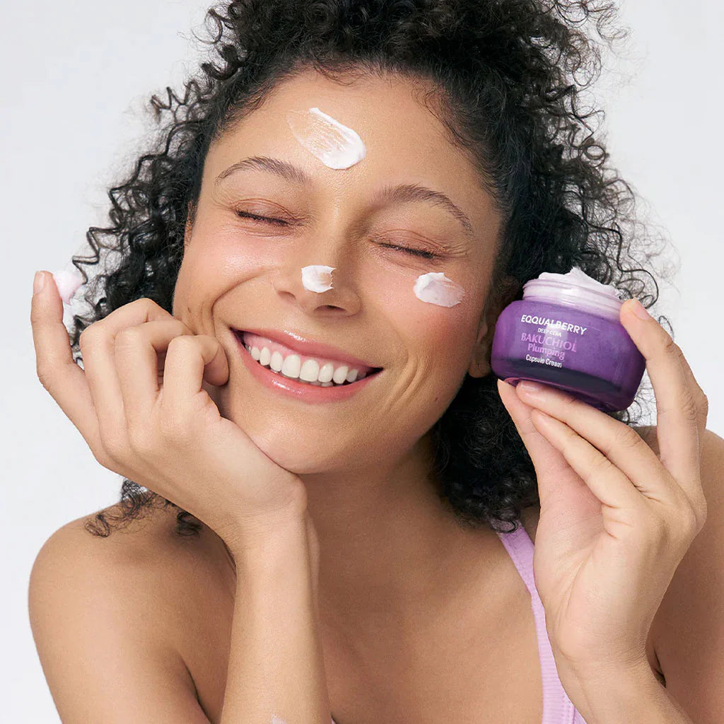 Woman applying cream to her face with a purple jar of Sk invent in the background