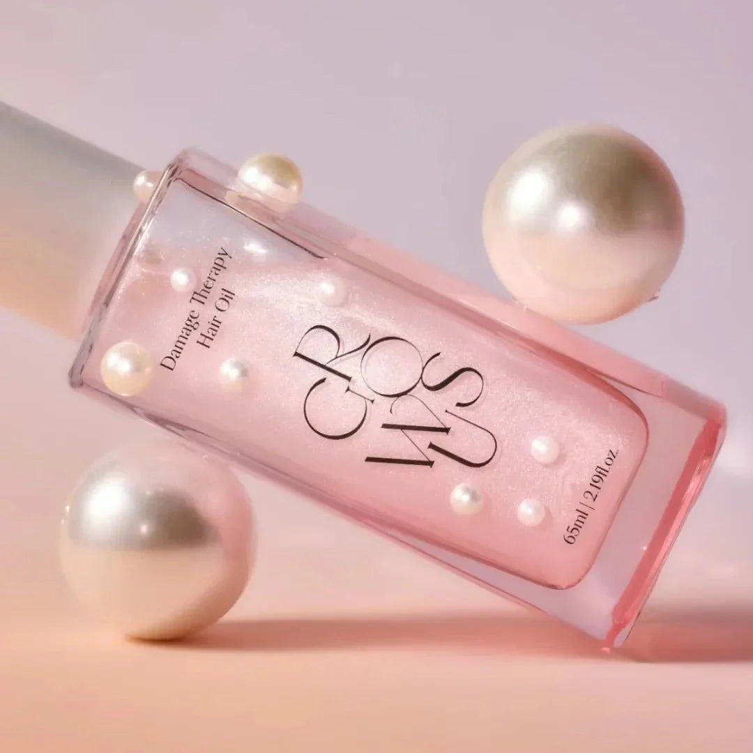 Pink bottle of hair oil with pearls on a soft pink background