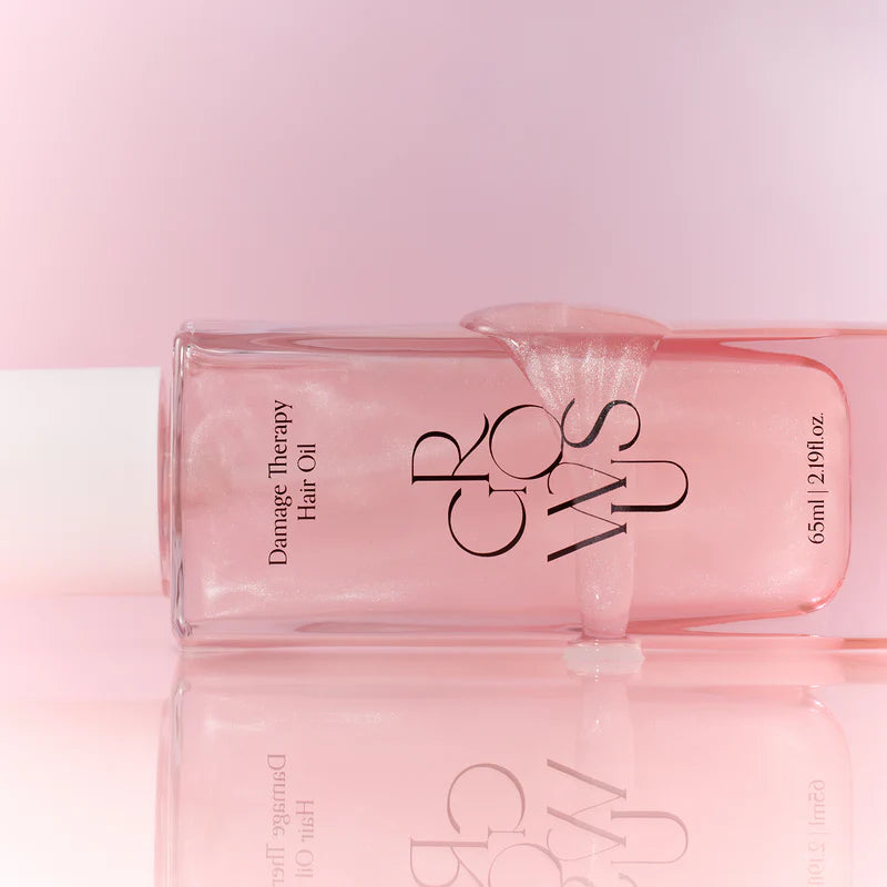 Pink hair oil bottle with 'GROWUS' branding on a pink background