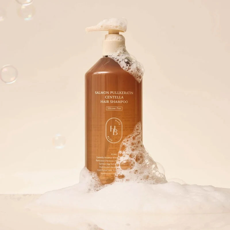 A bottle of salmon-pink pullkeratin gentlla hair shampoo by H&B, shown with white foam and bubbles against a warm beige background.
