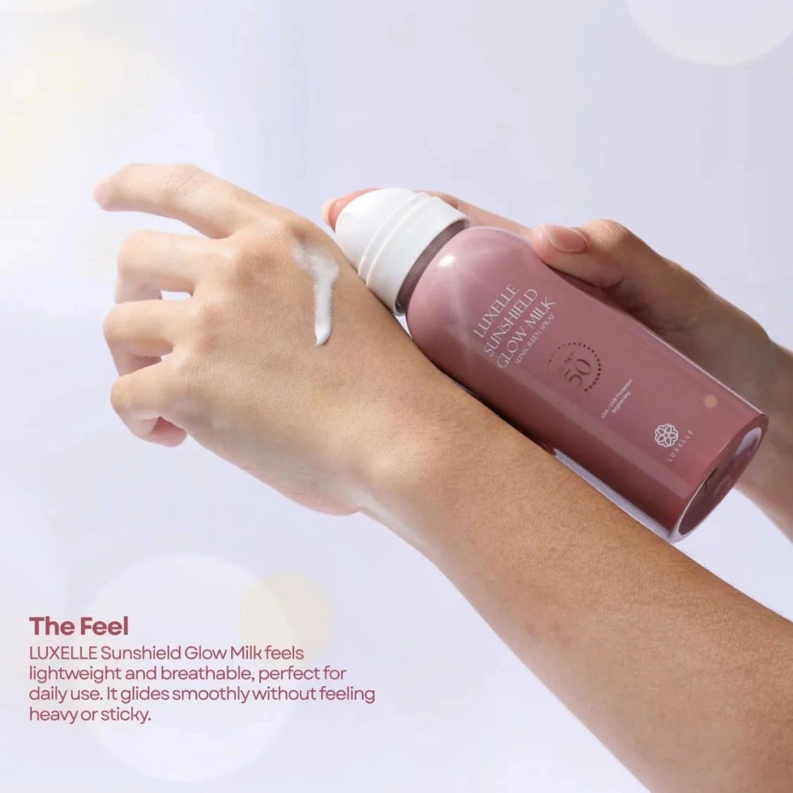Hand applying Luxelle Sunshield Glow Milk to a wrist with a white background