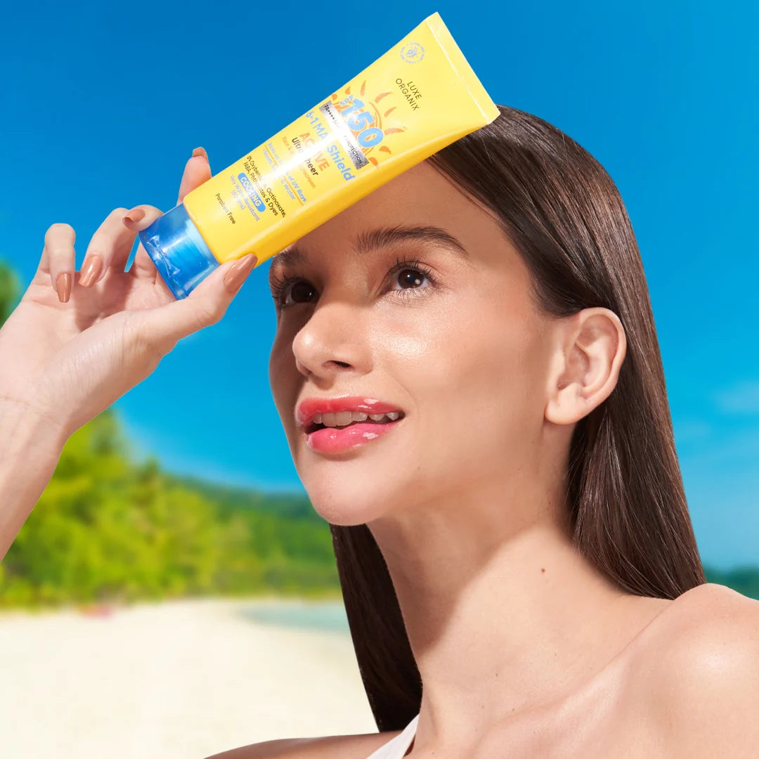 Woman applying sunscreen on a beach with a clear blue sky