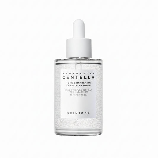 A clear glass bottle with a white dropper containing a transparent liquid, labeled as 'Madagascar Centella Tone Brightening Capsule Ampoule'.