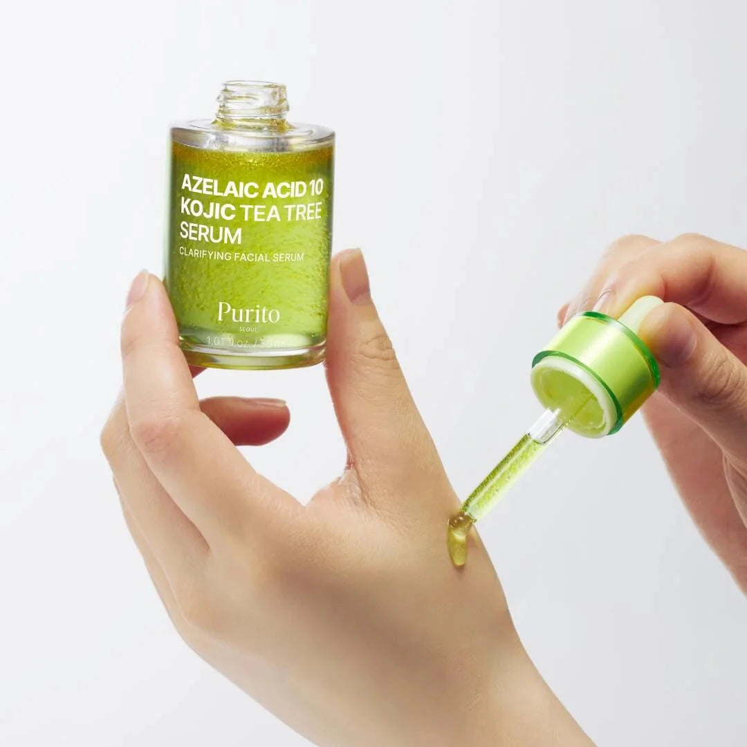 Hand holding a bottle of Purito Azelaic Acid 10 Kojic Tea Tree Serum with a dropper.