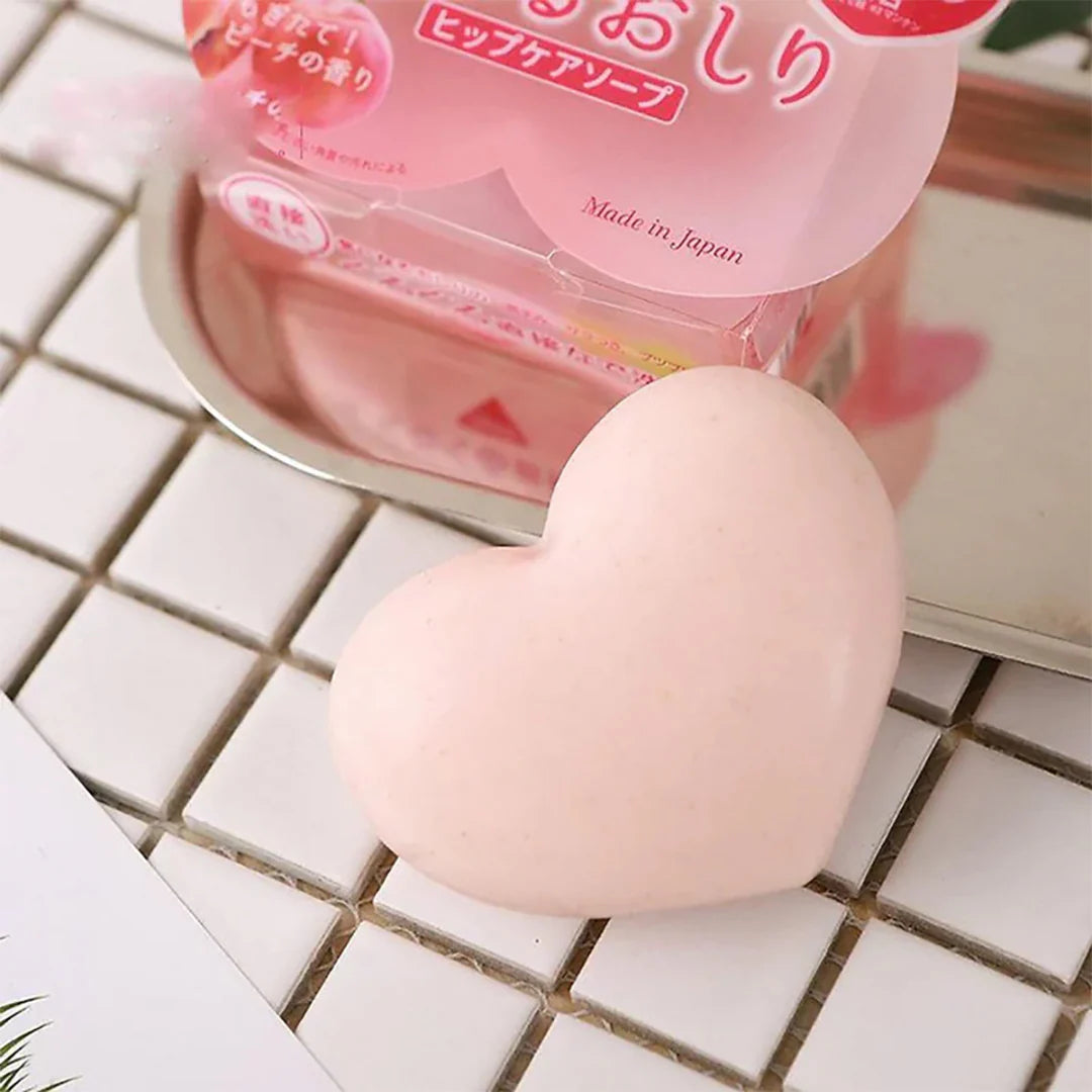Heart-shaped pink soap on a tiled surface with packaging in the background
