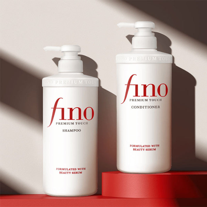 Two bottles of fino shampoo and conditioner on a red platform with a neutral background
