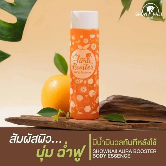 Orange bottle labeled 'Aura Booster' on a wooden surface with leaves and an orange fruit.