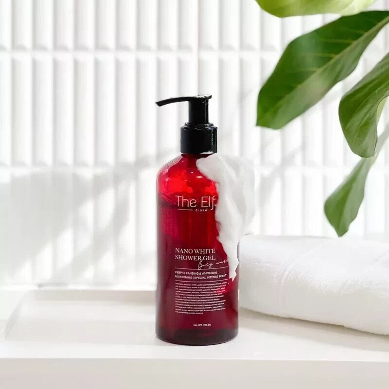 Red bottle of 'The Elf' Nano White Shower Gel on a white surface with a plant in the background