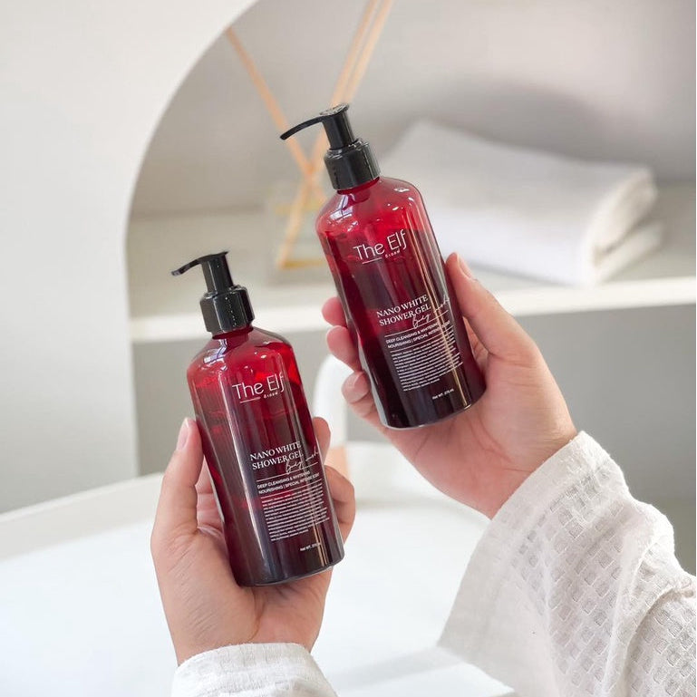 Two bottles of 'The Gin' product held by a person in a bathroom setting.