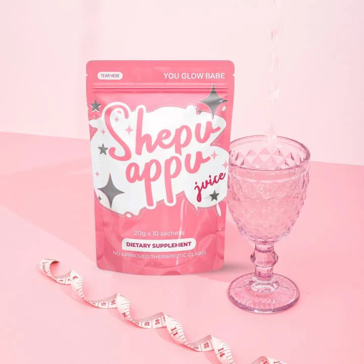 A pack of Shepu Appu slimming juice with a glass and a measuring tape on a pink background.