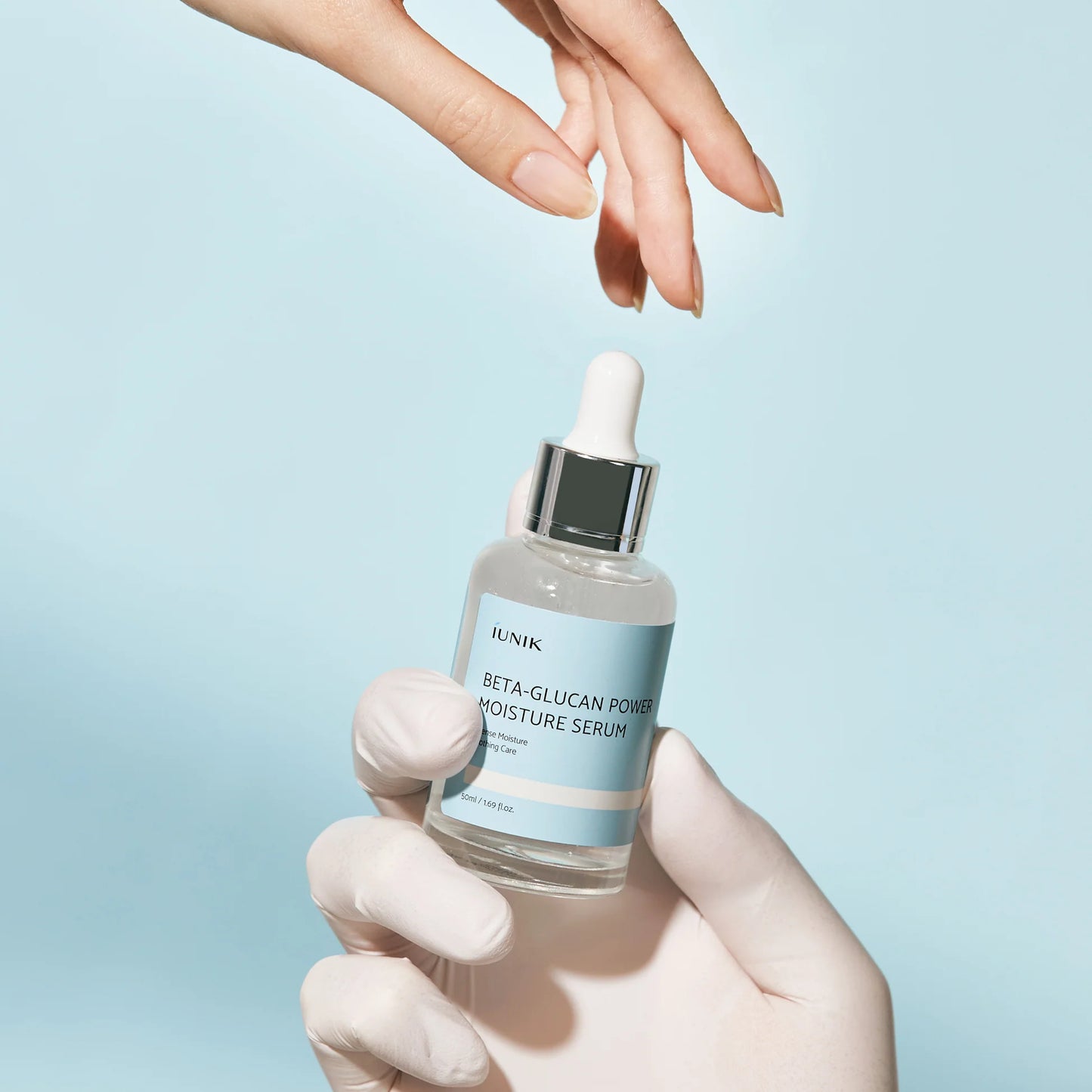 Hand holding a skincare serum bottle with a blue background